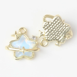 Close-up of golden star and planet charms with blue iridescent stone for jewelry making