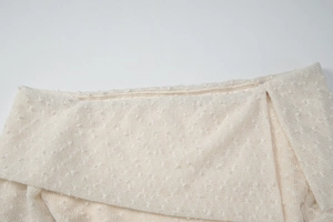 Close-up of off-white lace dress featuring polka dot texture and elegant neckline detail