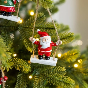 Resin Santa Claus swing ornament hanging on a Christmas tree with warm lights