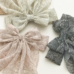 Detailed view of three paisley print fabric bow hair clips in green, pink and dark green