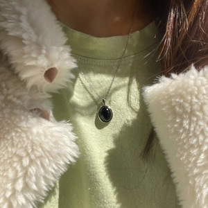 Close-up of minimalist 925 silver necklace featuring a sleek black oval pendant on a model