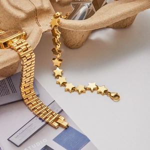 Detail of 18K gold stainless steel star bracelet and watch band on a stylish studio prop