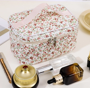 Detailed close-up of a large floral cosmetic bag with pink handle and zipper closure
