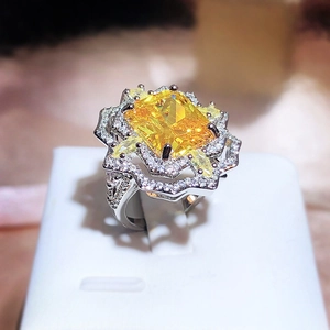 Macro view of a large yellow cushion-cut diamond ring with silver metal petal setting