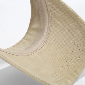 Dettaglio delle cuciture multistrato sulla visiera di un cappello beige in cotone twill