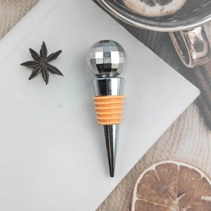 Zinc alloy disco ball wine stopper with orange silicone seal on a white notebook