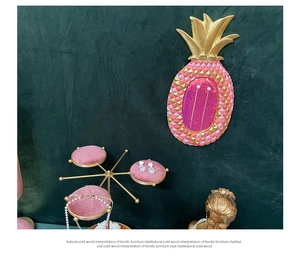 Pink pineapple wall board and gold rotating jewelry stand with pink velvet trays