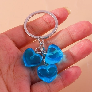 Detail of three transparent blue resin hearts on a polished silver metal keychain
