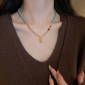 Gros plan d'un collier ras du cou en perles bleues avec un pendentif gourde dorée