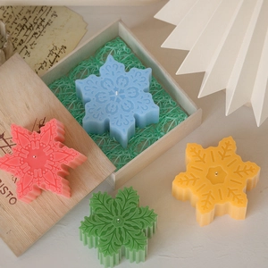 Bovenaanzicht van kleurrijke sneeuwvlokkaarsen met textuur in een feestelijke geschenkdoos