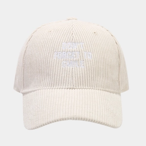 Detail of embroidered 'DON'T FORGET TO SMILE' text on cream corduroy baseball cap