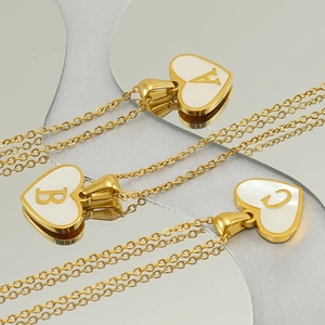 Macro view of gold heart pendants with shell inlay and engraved A, B, C letters