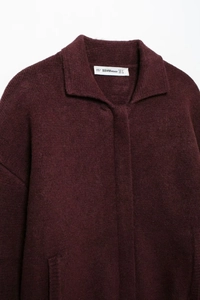 Détail du col d'un cardigan en maille bordeaux avec texture douce et étiquette de marque