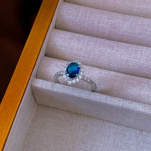 Dettaglio dell'anello ovale con zircone blu e diamanti in una scatola regalo