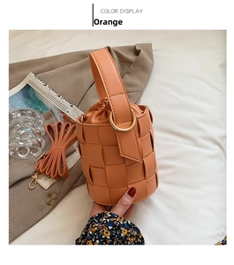 Detail of orange woven bucket bag with gold hardware and drawstring closure
