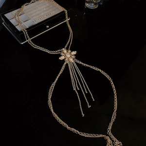 Detailed close-up of gold body chain featuring pearl flowers, rhinestones and fringe tassels