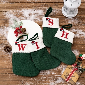 Detailed knit texture of four dark green Christmas stockings with red WISH embroidery