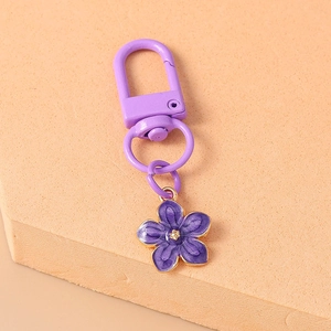Detailed macro view of a purple flower keychain with a golden edge and D-ring clasp