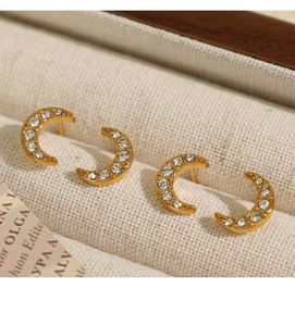Détail macro de boucles d'oreilles lune dorées avec cristaux dans un écrin