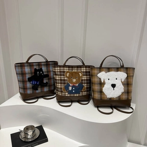 Three wool plaid tote bags with cartoon animal designs on white steps in a clean studio