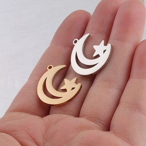 Close-up of gold and silver hollow moon star pendants on palm for size reference