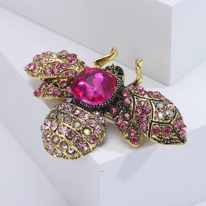 Macro shot of vintage gold bee brooch featuring pink crystals and sparkling rhinestones