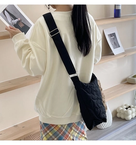 Rear view of a model wearing a black quilted tote bag with an adjustable wide strap