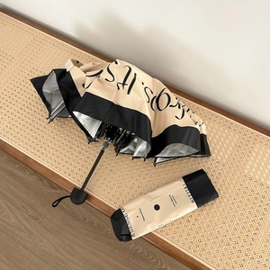 Detail of minimalist cream umbrella with sun protection coating on woven wood bench