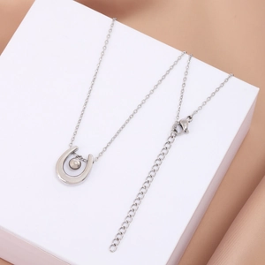 Detail of silver horseshoe pendant necklace with a metal bead on champagne silk fabric