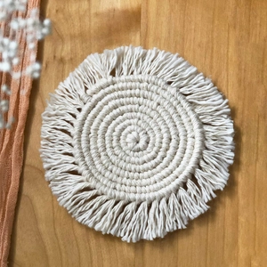 Handwoven Nordic cotton coasters with fringe decoration on a rustic wooden table