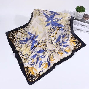 Close-up of silk scarf with blue leaf patterns and black borders on white background