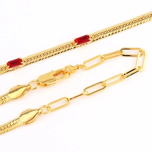 Macro view of 18K gold plated herringbone chain with red gemstone and paperclip link details