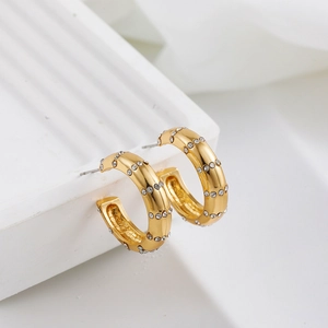 Vue macro de boucles d'oreilles en C plaquées or 18 carats avec rangées de diamants sertis