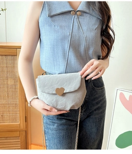 Détail de la pochette matelassée gris clair avec un fermoir en métal doré en forme de cœur