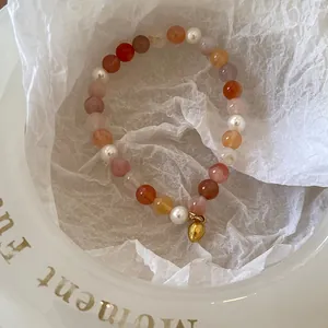 Détail d'un bracelet de perles colorées avec perles blanches et pendentif doré chic