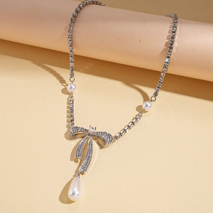 Détail du pendentif nœud argenté avec strass et perle goutte sur collier long