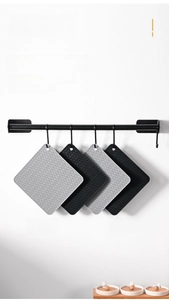 Detail of grey and black silicone pot holders with wave texture hanging on a kitchen rack