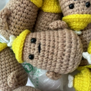 Close-up of handmade crochet potato dolls with yellow hats in bulk factory setting