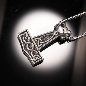 Gros plan du pendentif Mjölnir avec nœuds vikings et une tête de bélier sculptée