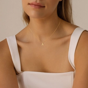 Elegant gold-plated letter A pendant necklace on cross chain worn by a female model