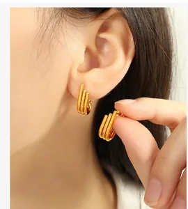 Close-up of minimalist triple-row gold-plated earrings worn to show the actual size
