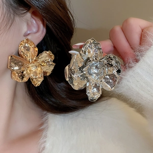 Macro detail of large metallic flower stud earrings with elegant hammered texture finish