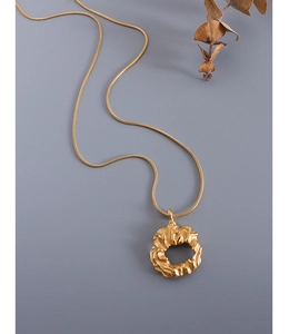 Detail of minimalist gold irregular pendant on a snake chain against a grey background