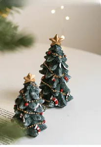 Close-up of resin mini Christmas trees with gold stars, red bows and candy canes