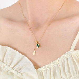 Golden necklace with emerald zircon square pendant and BABY engraved bar on model