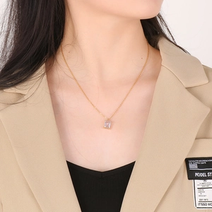 Detail of a square glass pendant on a gold titanium steel necklace worn by a model