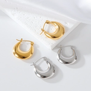 Detailed view of gold and silver chunky crescent hoop earrings on elegant silk background