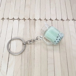 Macro shot of bubble tea keychain with green liquid and mini pearls on wood background