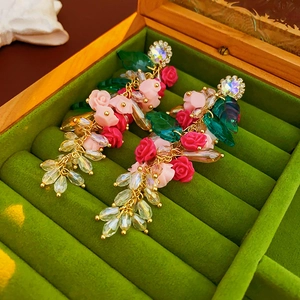 Détail de boucles d'oreilles vintage à pampilles, roses roses et cristaux, boîte en velours