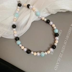 Close-up of pearl and colorful glass bead necklace on book with silver clasp